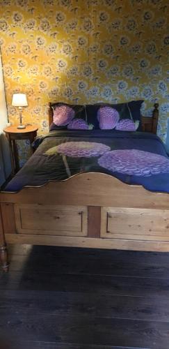a wooden bed with purple sheets and pillows in a bedroom at Maison Fleurie in Coulonges