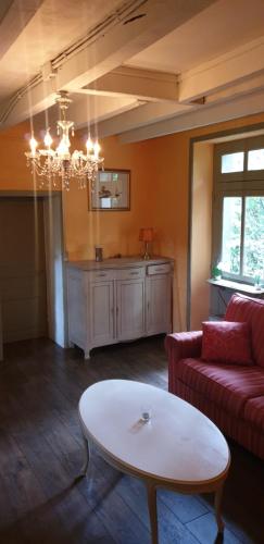 ein Wohnzimmer mit einem roten Sofa und einem Tisch in der Unterkunft Maison Fleurie in Coulonges