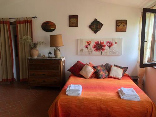 Cette chambre comprend un lit avec des draps orange et une commode. dans l'établissement Monolocale La Mimosa, à Elmo