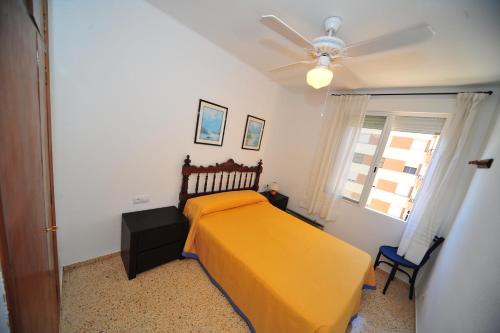 1 dormitorio con cama amarilla y ventilador de techo en Veracruz Orange Costa, en Benicàssim