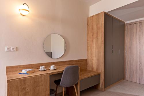 a room with a desk with a chair and a mirror at Hotel Kathrin Beach in Adelianos Kampos