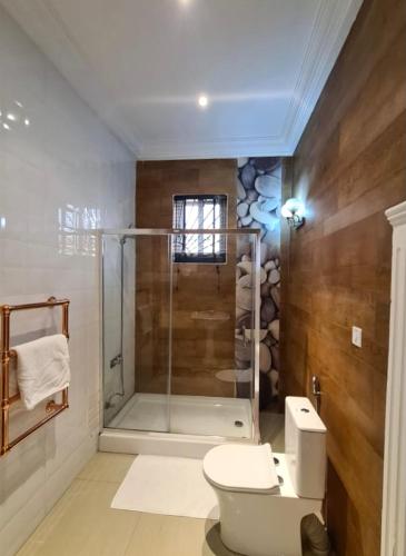 een badkamer met een douchecabine en een toilet bij Greystone Mansion in Accra