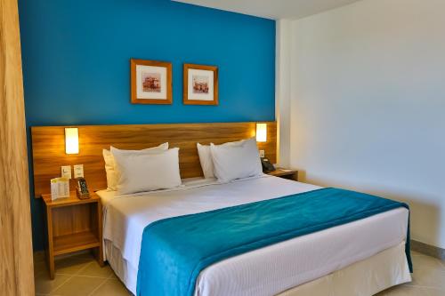 a bedroom with a large bed with a blue wall at ARCUS Hotel By Atlântica in Aracaju