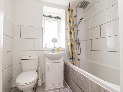 a bathroom with a toilet and a tub and a sink at Jam Pot Cottage in Preston