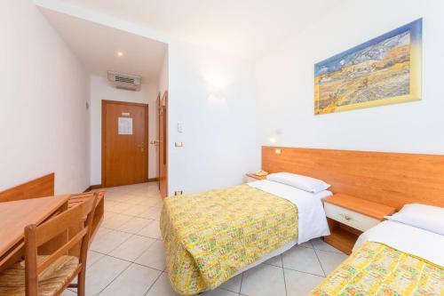 a hotel room with two beds and a table at Hotel New Aurora Venice in Marghera