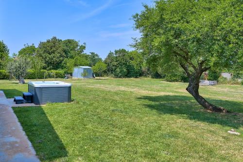 a smallshed sitting in a field next to a tree at Holiday house Mirna with swimming pool and jacuzzi in Pula