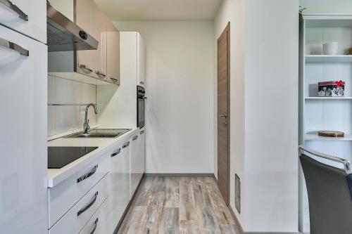 a kitchen with white cabinets and a wooden floor at Holiday house Mirna with swimming pool and jacuzzi in Pula