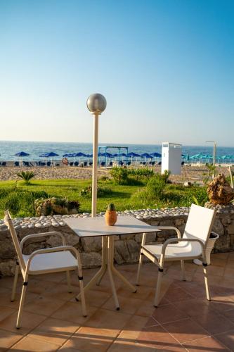 a table and two chairs with the ocean in the background at Hotel Kathrin Beach in Adelianos Kampos