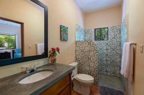 a bathroom with a sink and a toilet and a mirror at Zen Casita near Playa Colorado! in Tola