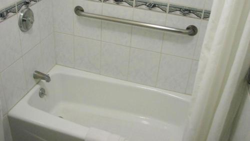 a white bath tub in a bathroom with a shower curtain at Motel 6 Glendale CA Pasadena Burbank Los Angeles in Glendale