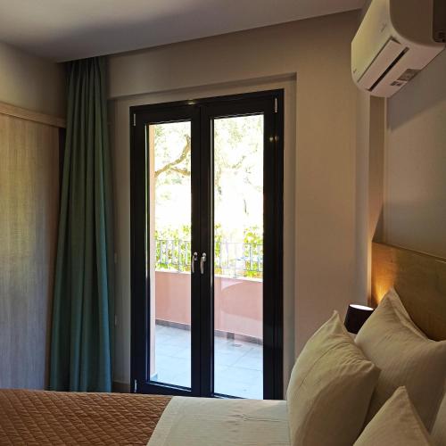 a bedroom with a bed and a sliding glass door at Trianon Studios in Tsilivi