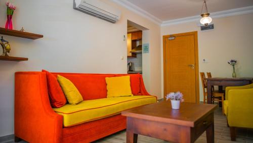 an orange couch with yellow pillows in a living room at Dores Residence in Turunc