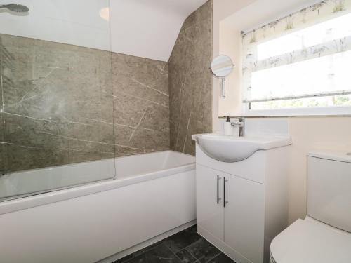 a bathroom with a sink and a tub and a toilet at Ammerham Farm Cottage in Chard