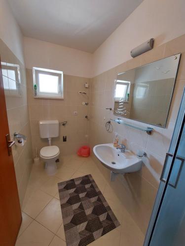a bathroom with a sink and a toilet and a mirror at Apartment Jure in Primošten