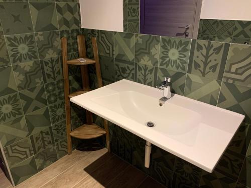 a white sink in a bathroom with green tiles at Sala dell Estate Guest House in Secchia