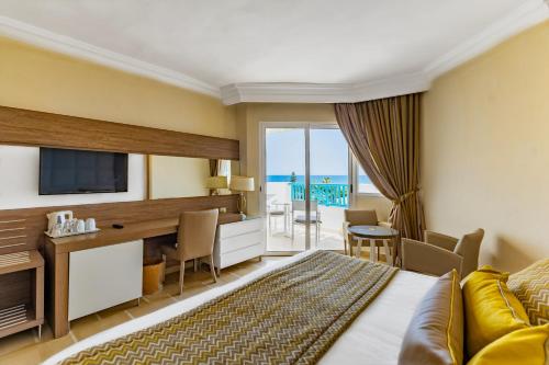 a hotel room with a bed and a desk and a television at Sentido Bellevue Park in Port El Kantaoui