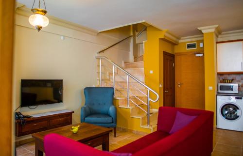 a living room with a couch and a chair and a staircase at Dores Residence in Turunc