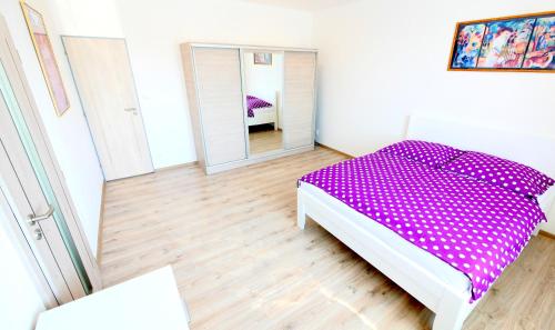 1 dormitorio con cama morada y espejo en Soukromý - plně vybavený byt 2+KK en Znojmo