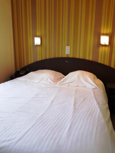 a bed with white sheets and pillows on it at Auberge de la Baie in Ardevon
