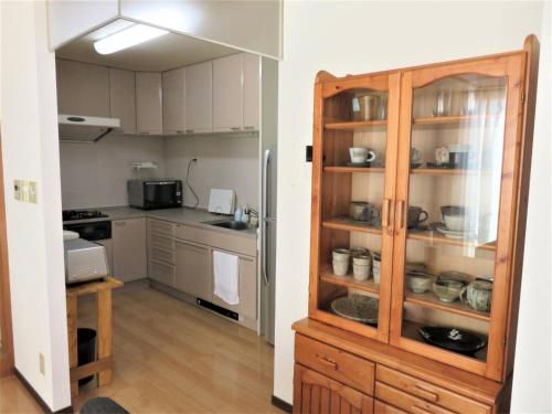 Monzen House Dormitory type- Vacation STAY 49374v في Kasama: مطبخ مع خزانة خشبية مع أطباق فيها