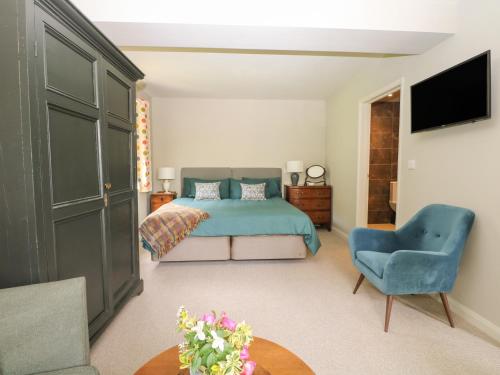 a bedroom with a bed and a blue chair at The Barn at Sandhole Cottage in Tonbridge
