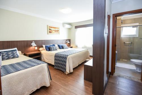 a hotel room with two beds and a bathroom at Hotel Kehl Haus in Gramado