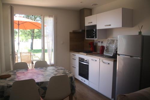 une cuisine avec une table et un réfrigérateur blanc dans l'établissement L Ostalet Tarn et Garonne, à Bressols