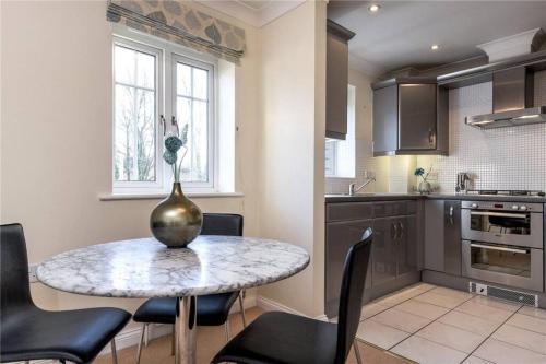 a kitchen with a table with chairs and a vase on it at Sunny 1 bed apartment in a quiet central location in Basingstoke