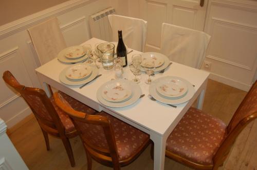 a white table with plates and a bottle of wine at Beaune Residence appartement in Beaune