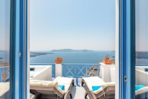 a balcony with chairs and a view of the ocean at Golden Grey Goose in Fira
