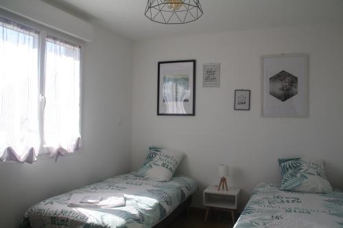 deux lits dans une chambre avec des murs et des fenêtres blancs dans l'établissement L Ostalet Tarn et Garonne, à Bressols