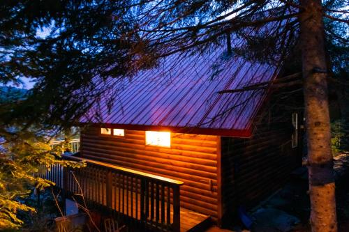 a cabin with a lit up roof at night at Le petit chalet sur le lac in Sainte-Marguerite