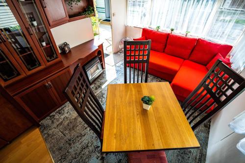 salon z drewnianym stołem i czerwoną kanapą w obiekcie Namelių nuoma Giruliuose w Kłajpedzie