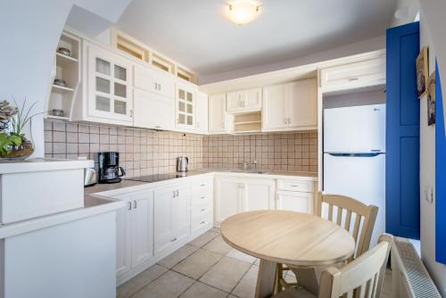 a kitchen with white cabinets and a wooden table at Golden Grey Goose in Fira