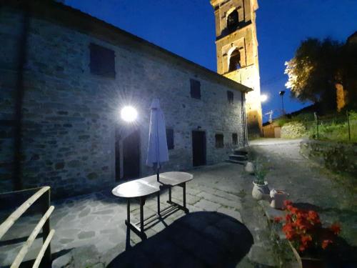 a table with an umbrella next to a building with a clock tower at THE DORMOUSE - Il Ghiro in Reusa