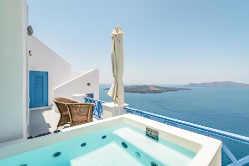 a jacuzzi tub on a balcony overlooking the ocean at Golden Grey Goose in Fira