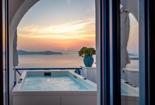 a hot tub in a room with a view of the ocean at Golden Grey Goose in Fira