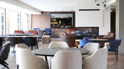 a restaurant with tables and chairs and a bar at Best Western Plus Le Fairway Hotel & Spa Golf d'Arras in Anzin-Saint-Aubin