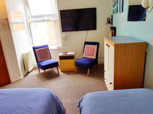 a bedroom with two chairs and a tv on the wall at Cumbria Guest House in Lytham St Annes