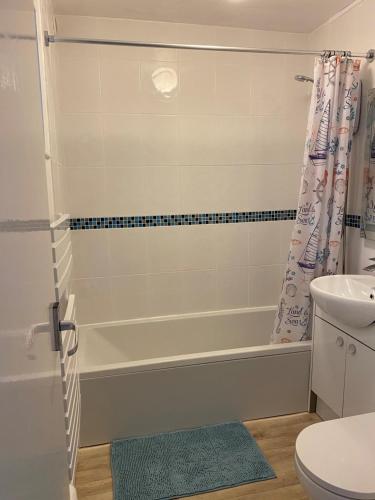 a bathroom with a tub and a toilet and a shower curtain at Vitamin Sea with a Sea View and Parking in Lyme Regis