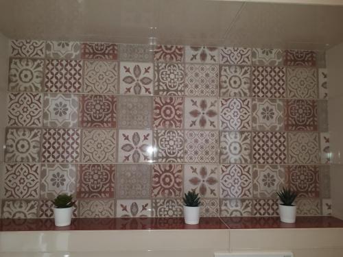 a tiled wall with three potted plants on a shelf at Casa ERMES 151 in Floridia