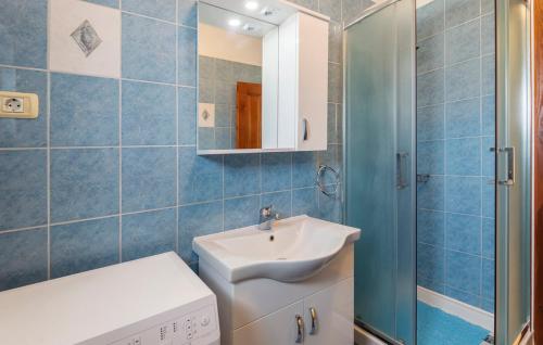 a blue tiled bathroom with a sink and a shower at Apartment Matea in Ližnjan