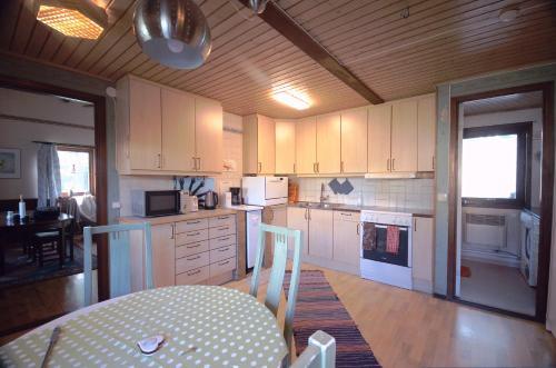 a kitchen with white cabinets and a table and a dining room at Gäststugan in Skara