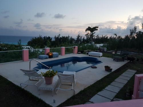 a swimming pool with chairs and the ocean in the background at Bermuda Connections Guest House in Southampton
