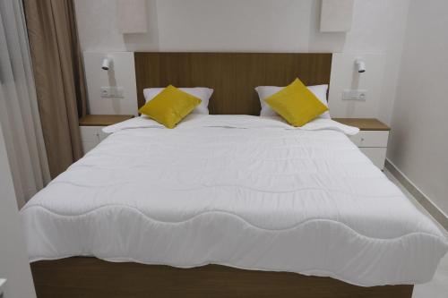 1 cama blanca grande con 2 almohadas amarillas en Résidence jannat, en Fnidek