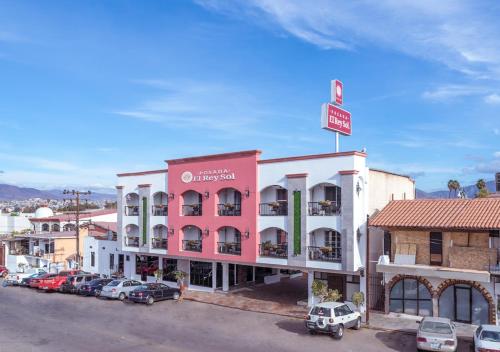 a pink and white building with cars parked in a parking lot at Hotel Posada El Rey Sol in Ensenada