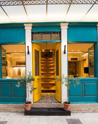 a blue building with a yellow door and stairs at Libretto Suites in Lefkada Town