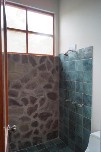 a bathroom with a shower with a stone wall at Indano Art Lodge in Lamas