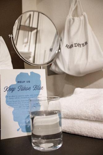 a glass of water next to a mirror and towels at PlumpJack Inn in Olympic Valley