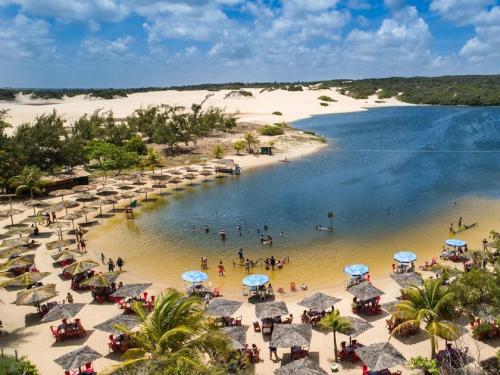 una playa con sombrillas y gente en el agua en Sonia Flats Arituba Tropical - Flat vista mar em frente à Praia de Camurupim, en Nísia Floresta